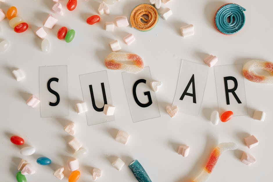 Flat lay of assorted colorful candies around the word 'SUGAR' on a white background.